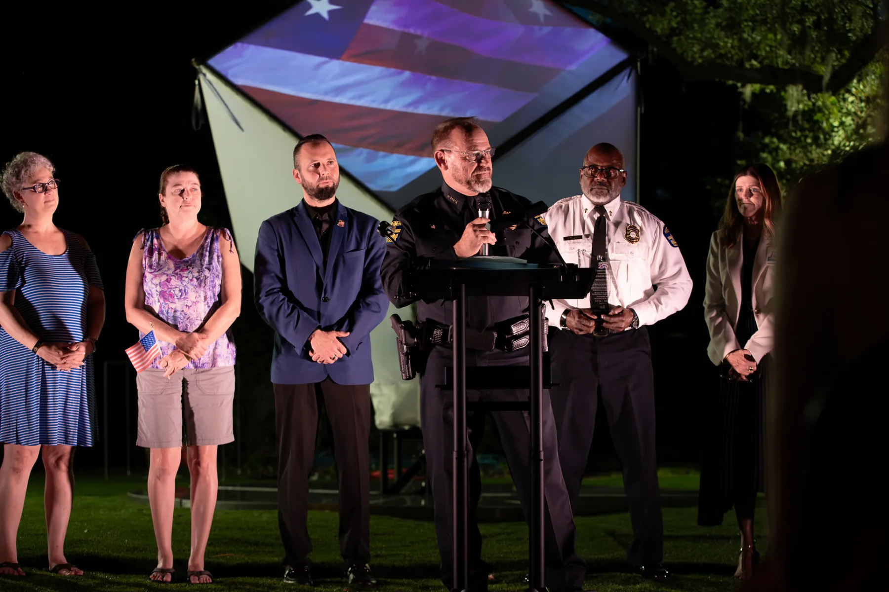 Chief David Ogden speaks at the outdoor lectern with Windermere leaders and community partners standing behind him.